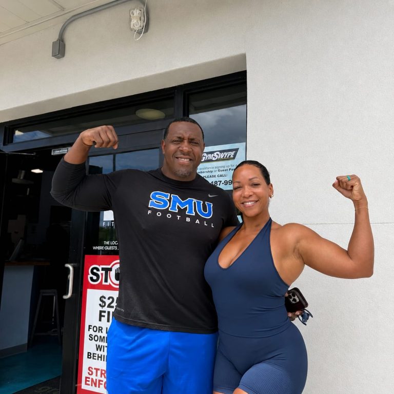 Two Grayton Beach Fitness members flexing their arms outside the gym’s front entrance