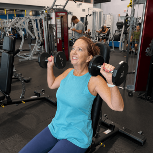 Woman using a seated shoulder press machine at Grayton Beach Fitness, a gym on 30A near Grayton Beach