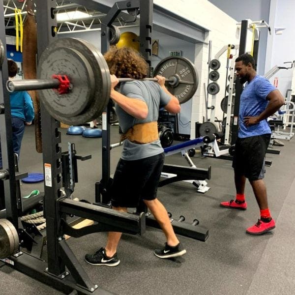 Members training in the squat rack and free-weight area at Grayton Beach Fitness