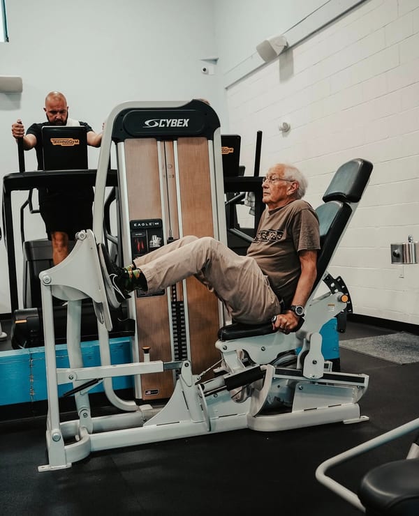 A member training on the Cybex line with a trainer at Grayton Beach Fitness